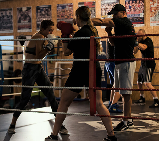 Two fighters getting trained in ring by boxing coach